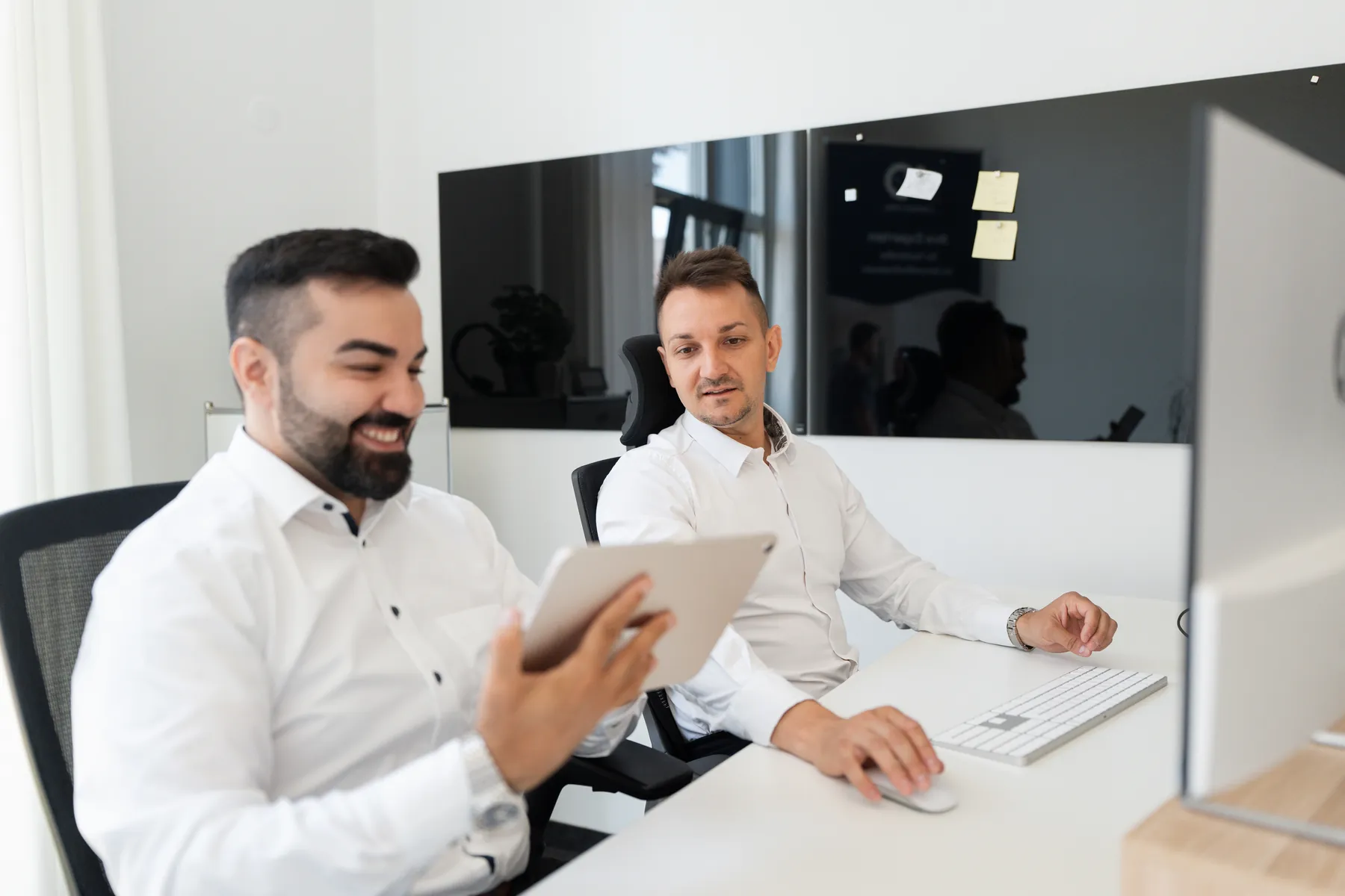 Zwei Mitarbeiter von AO Consulting stimmen den Auftritt einer Praxis am Tablet ab